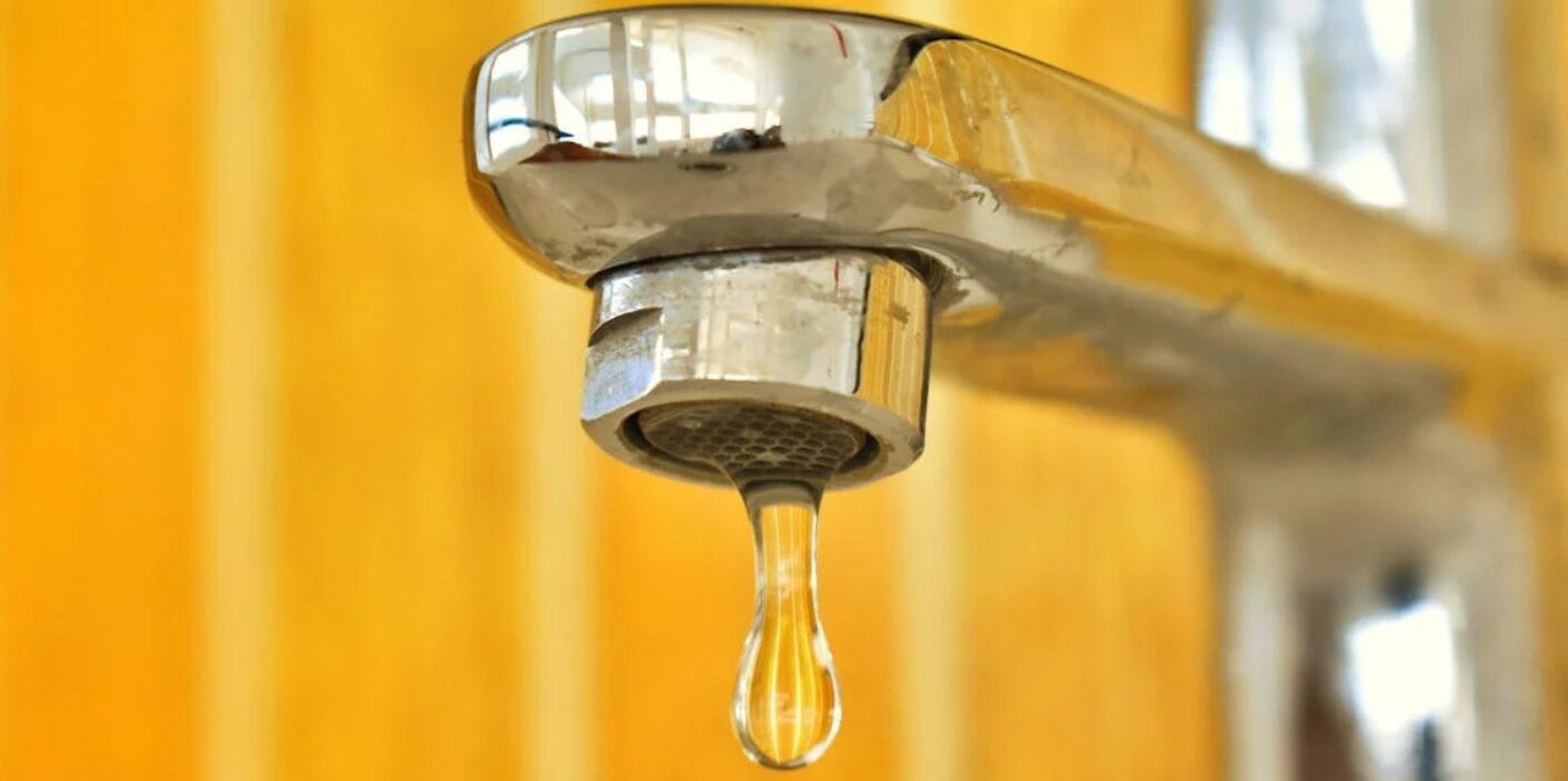 Close-up of a dripping faucet showcasing plumbing fixtures.