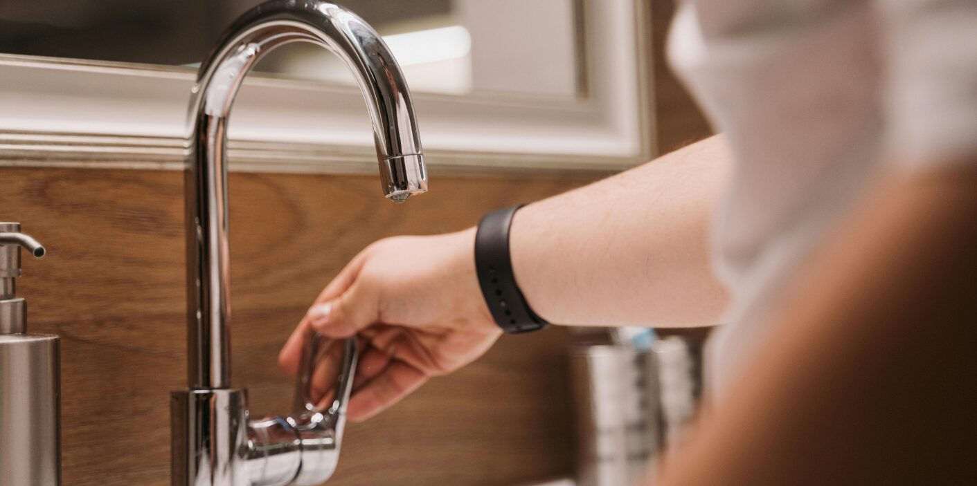 Person turning on a faucet, representing common DIY plumbing myths and misconceptions about home plumbing fixes